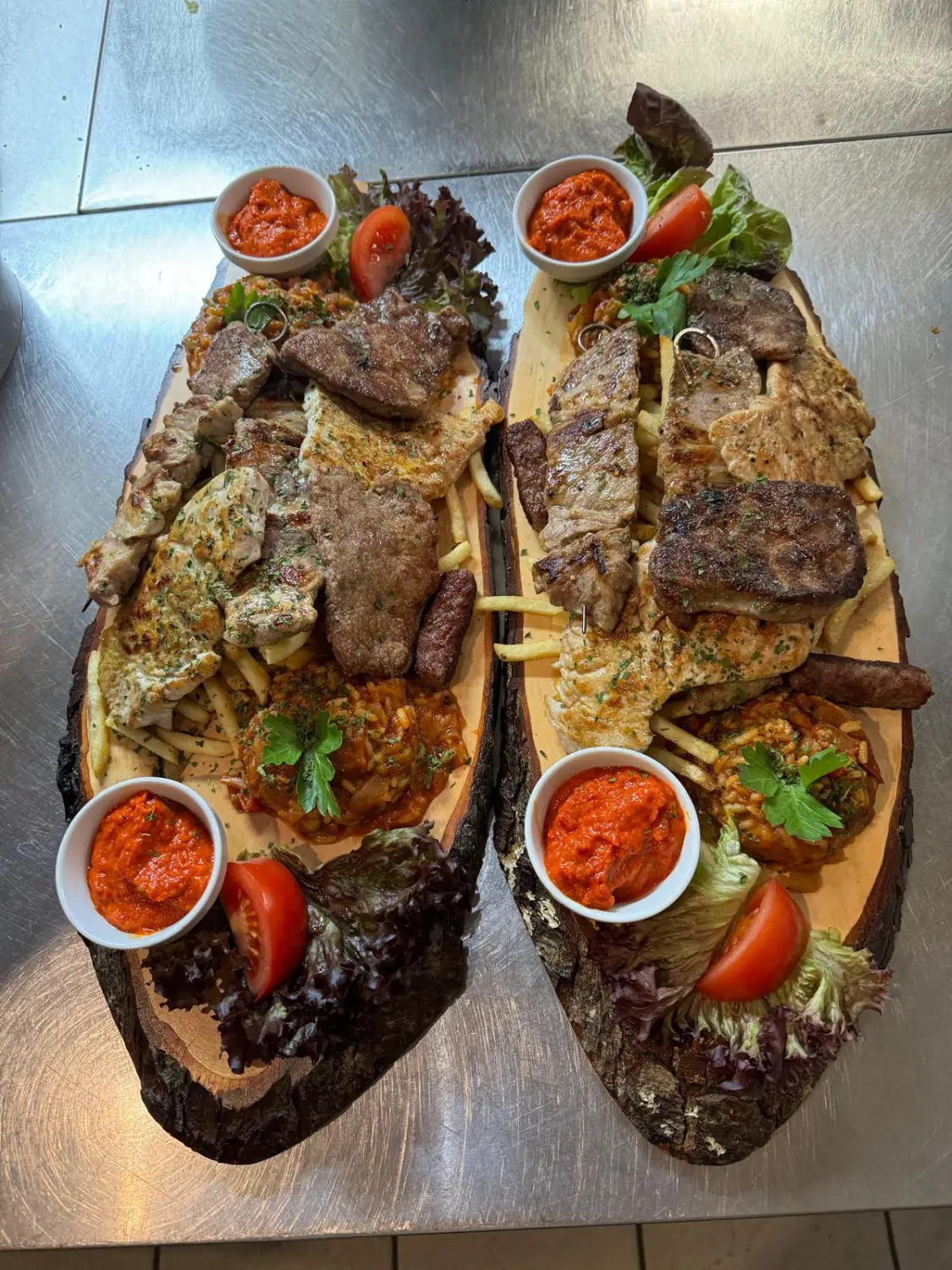 Balkan Grill - Balkanische Küche, serviert auf einem Holzbrett mit Pommes frites und Soße